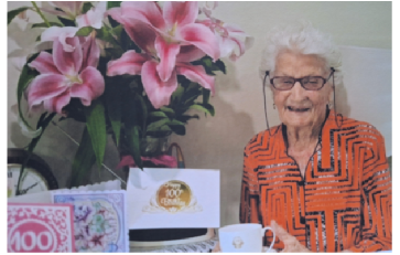 Betty Adam celebrating her 100th birthday, surrounded by cards and flowers